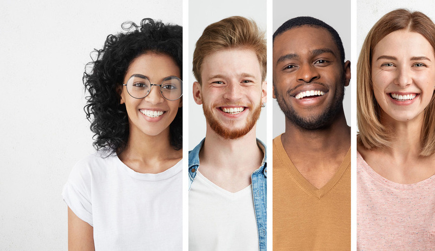 Four 20ish age adults smiling - a black/Hispanic woman with glasses, white man with red hair, black man with a beard and a white woman