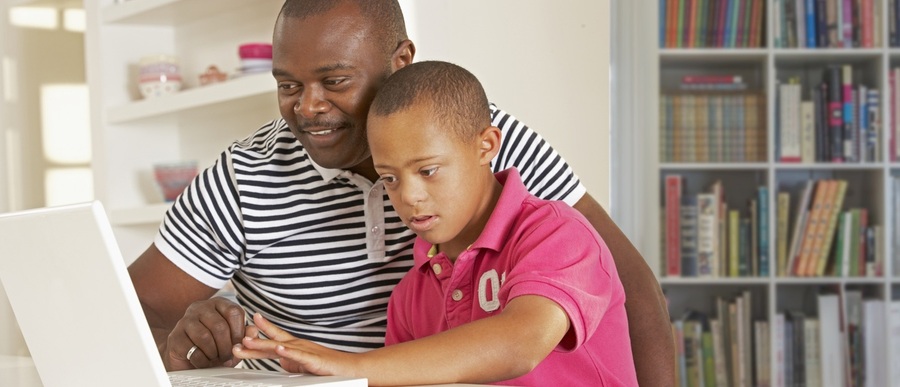 adult African American man working on something educational with young African American boy