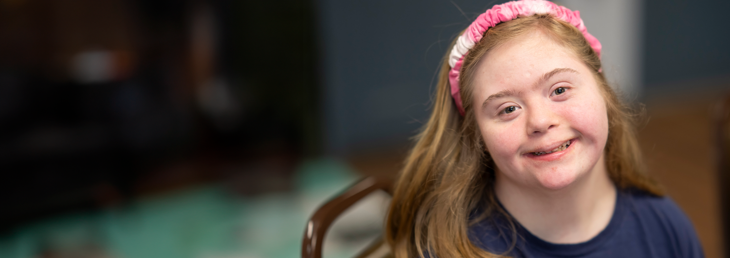 Contact Us Have a question? We're here to help! with photo of a young girl with Down syndrome smiling