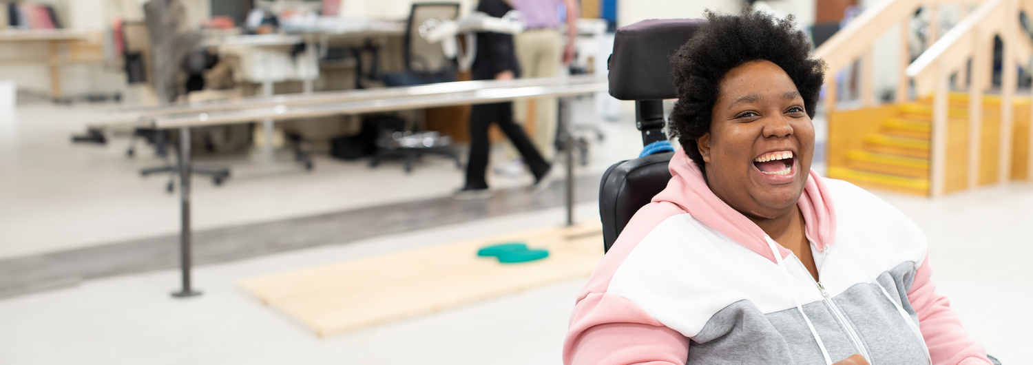 Publications. A young black woman using a wheelchair smiles.