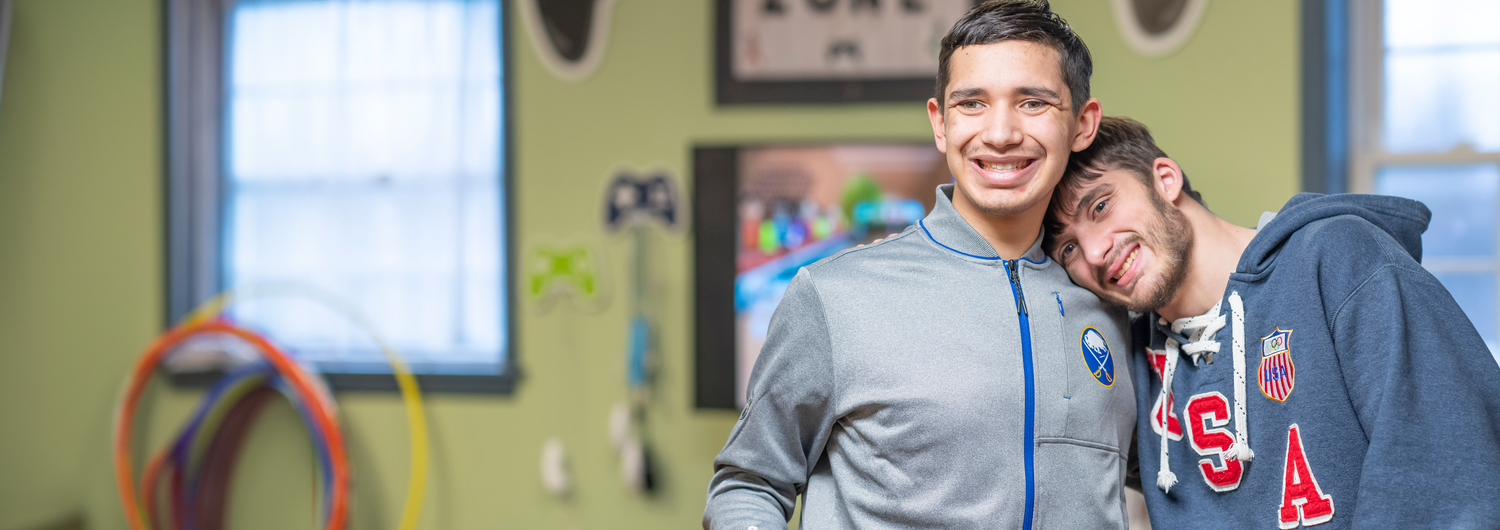Support Make a difference in the lives of people with special needs. Two young men smile and pose while playing a video game at People Inc. Respite.