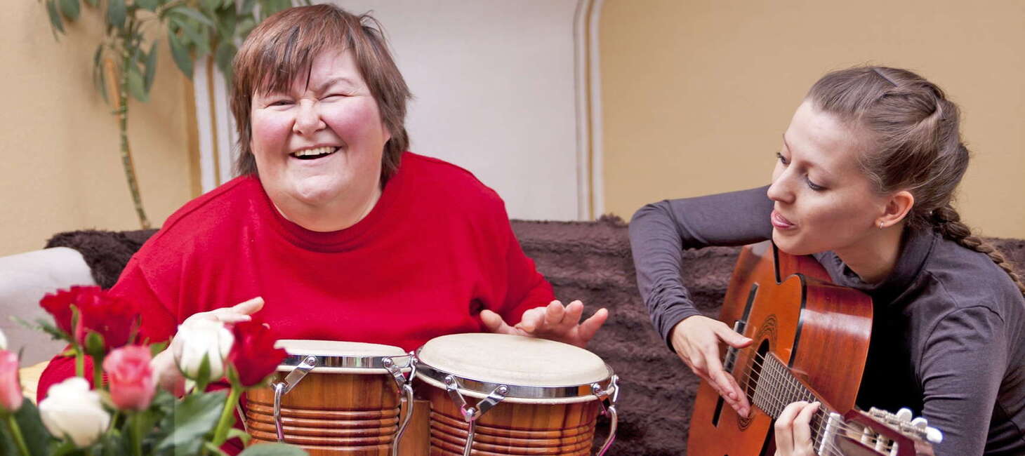 Young woman playing the bongos and a woman playing the guitar