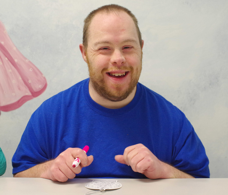 Man in blue shirt holding a marker smiling