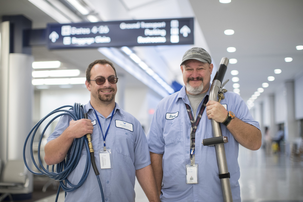 two men carrying equipment for commercial janitorial cleaning