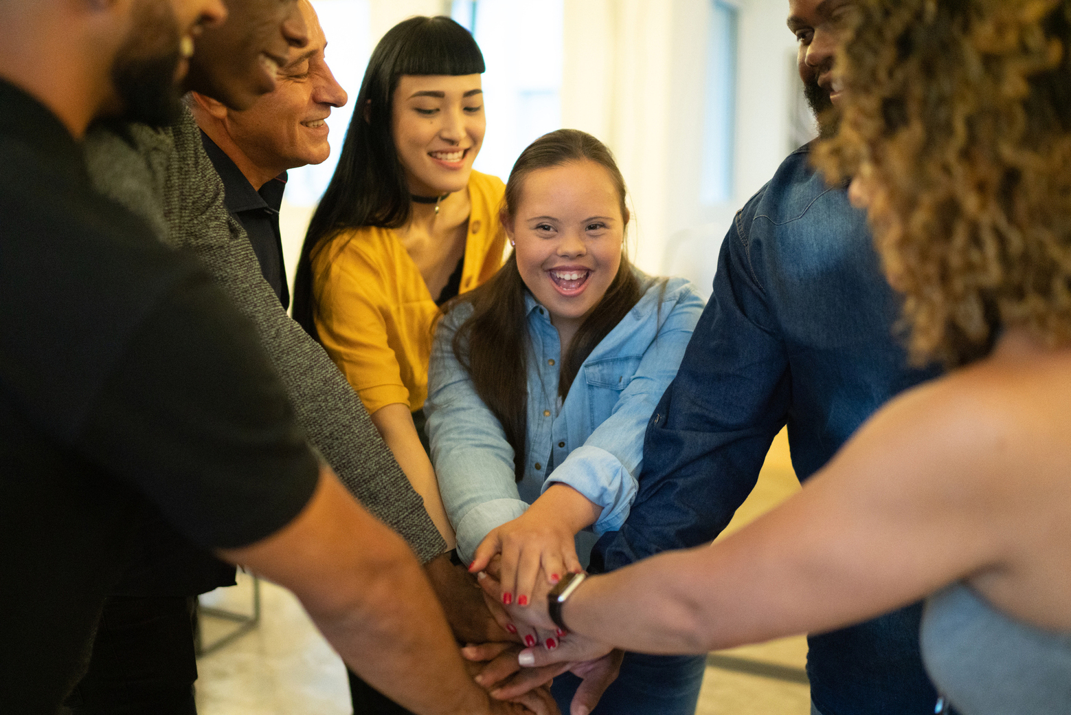 Girl with Downs syndrome joining hands with other people