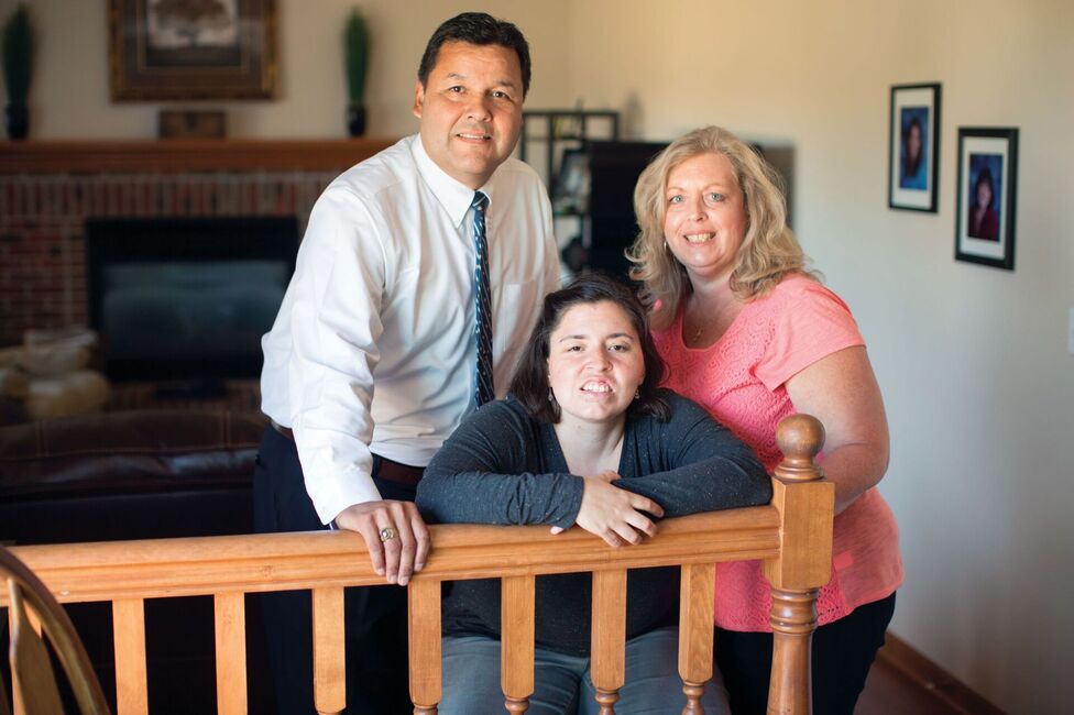 Three people: father, mother and daughter leaning on a wood railing