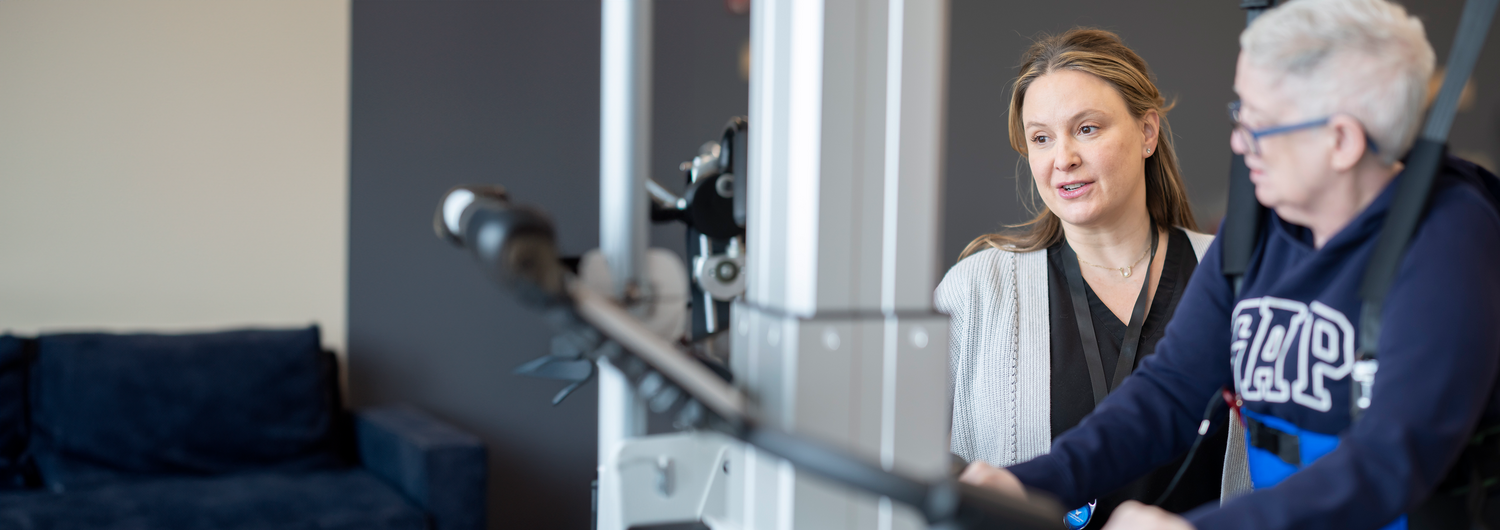 Woman staff advises patient on an exercise bike.