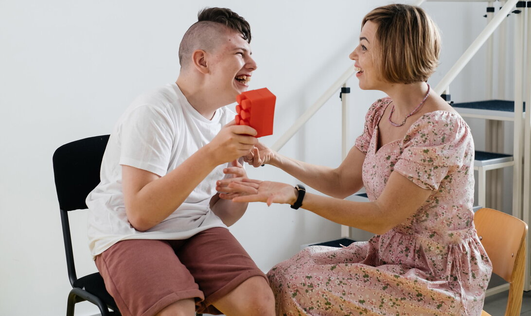 Occupational therapist woman works with young man holding a block