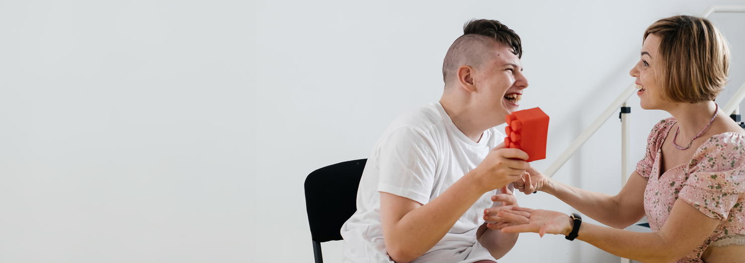 Occupational therapist woman works with young man holding a block