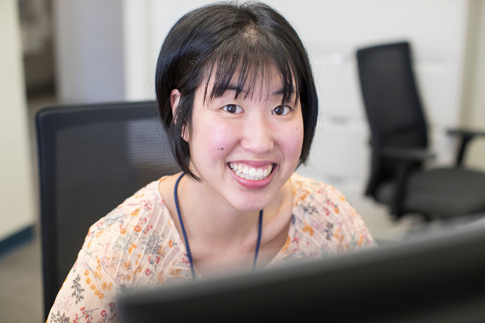 Asian young lady working at a computer smiling