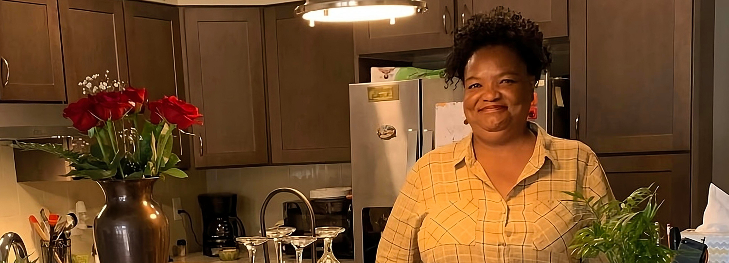 Black woman smiling in her apartment kitchen
