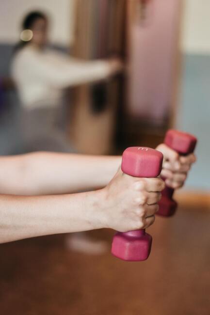 Two arms extend, holding a pair of red weights