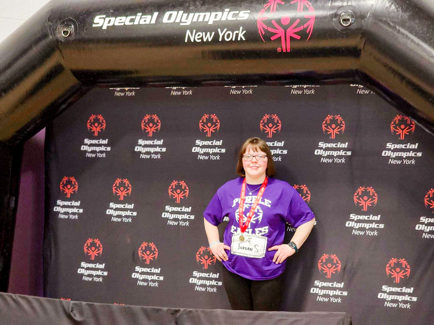Medal Winner Posing in Front of Special Olympics Logo