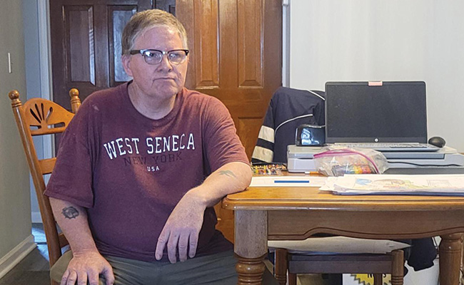 Robert sits at the table inside of his apartment