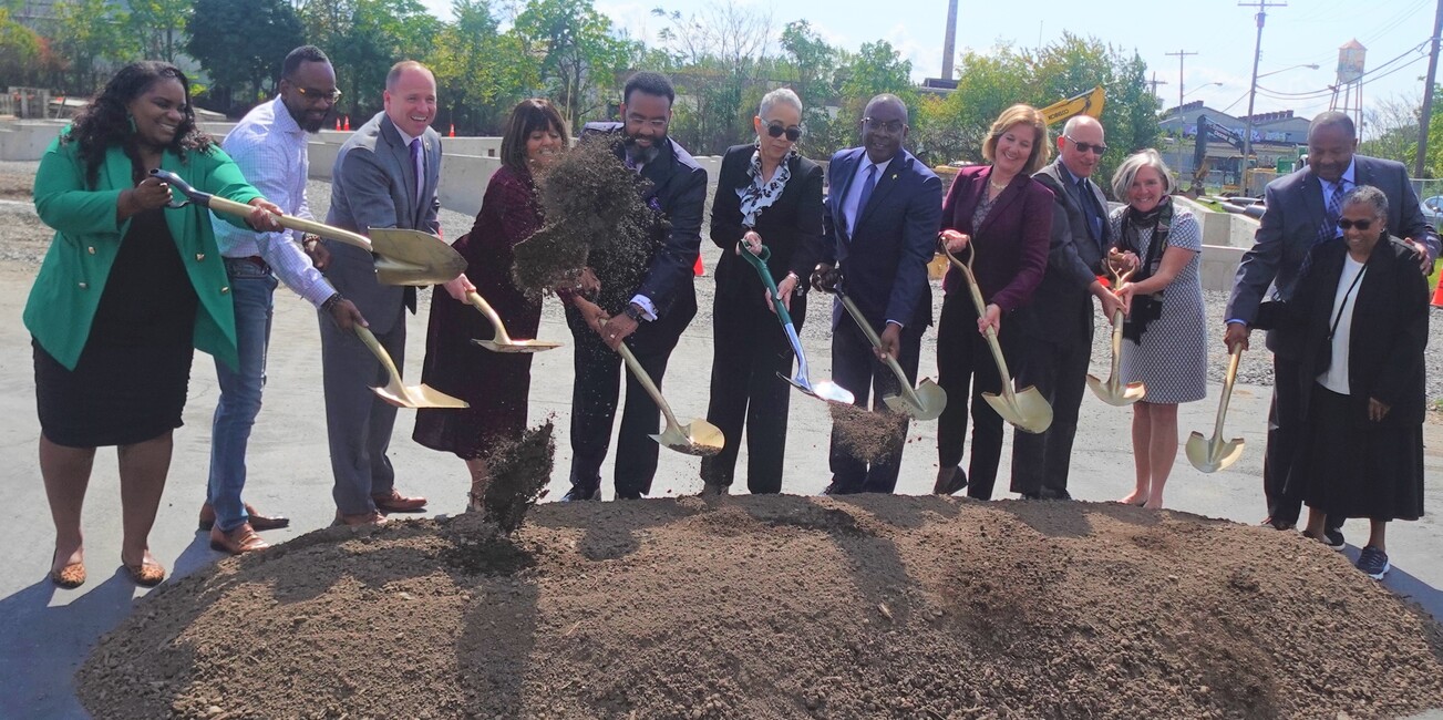 Twelve people who represent Mt. Olive Development Corporation, People Inc., as well as several government and community leaders, scooping dirt with shovels as part of the ceremonial Mt. Olive Senior Manor groundbreaking.