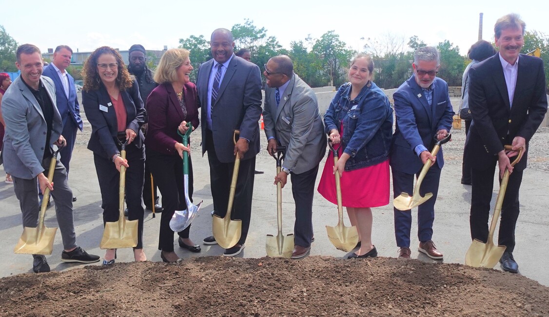 Eight people who represent Mt. Olive Development Corporation, and People Inc., scooping dirt with shovels as part of the ceremonial Mt. Olive Senior Manor groundbreaking.