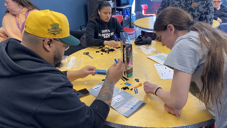 People sitting around a table working on assembling Lego projects