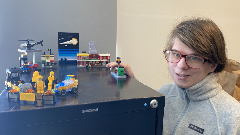 Woman with glasses shows a display of Lego projects