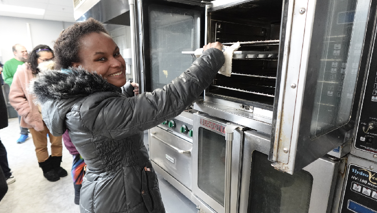 Woman taking a muffin pan out of the oven