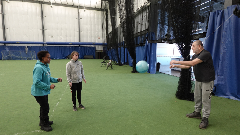 Three people playing catch inside