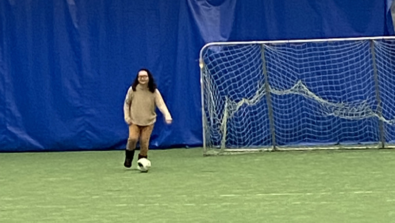 Woman kicking soccer ball and net